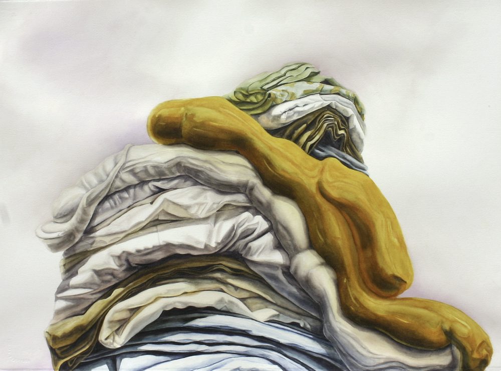 Watercolor painting of folded clothes and fabrics. The fabrics are layered on top of each other in a mountain form, with the horizontal lines of the folds appearing like layers of geological strata. There is light blue at the bottom, shades of light grays and browns in the middle, an orange diagonal that dips down to the lower right corner, and light greens on the top of the mound. The background is mostly white with light pinks and grays.