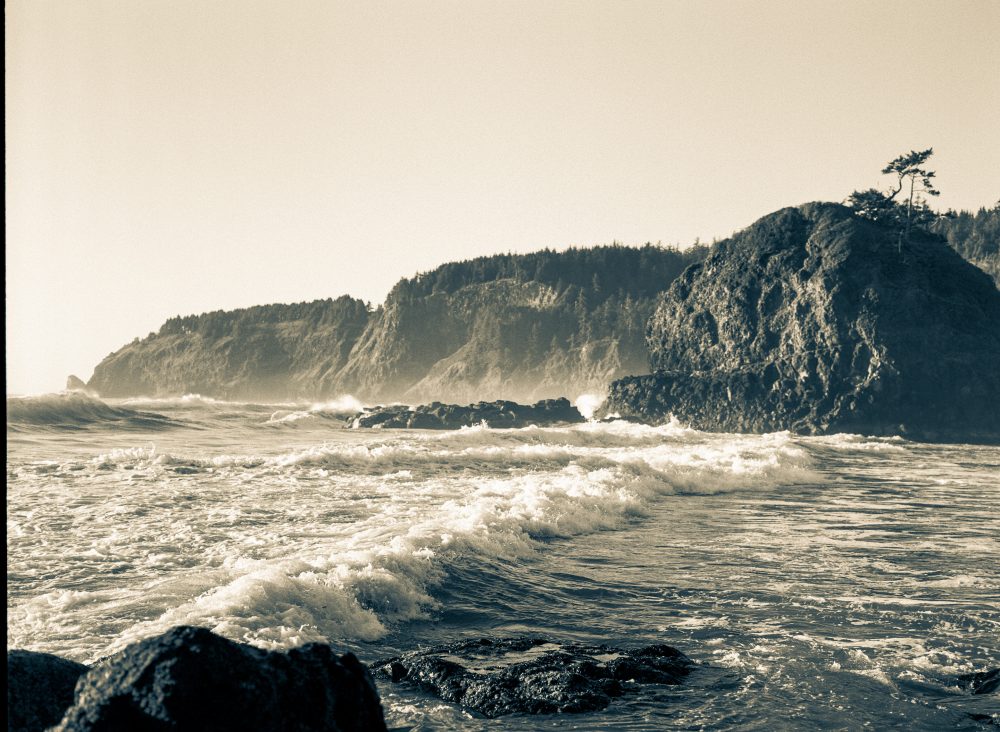 Waves crashing along the coast with a sea stack in midframe.