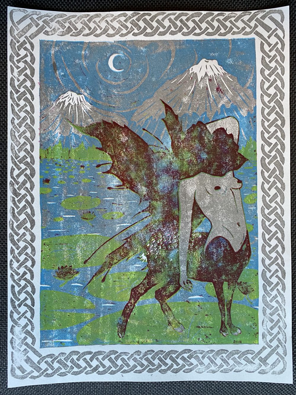 A reductive relief print made out of gray, blue, yellow, and red of a deer centar woman with a lotus head and fairy wings upon a lily pad in a lake with mountains and a night sky in the background.