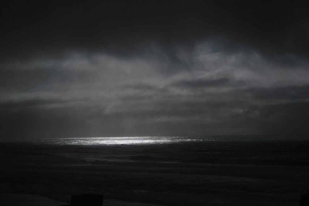A beam of light coming out of the clouds and shining on the ocean.