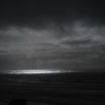 A beam of light coming out of the clouds and shining on the ocean.