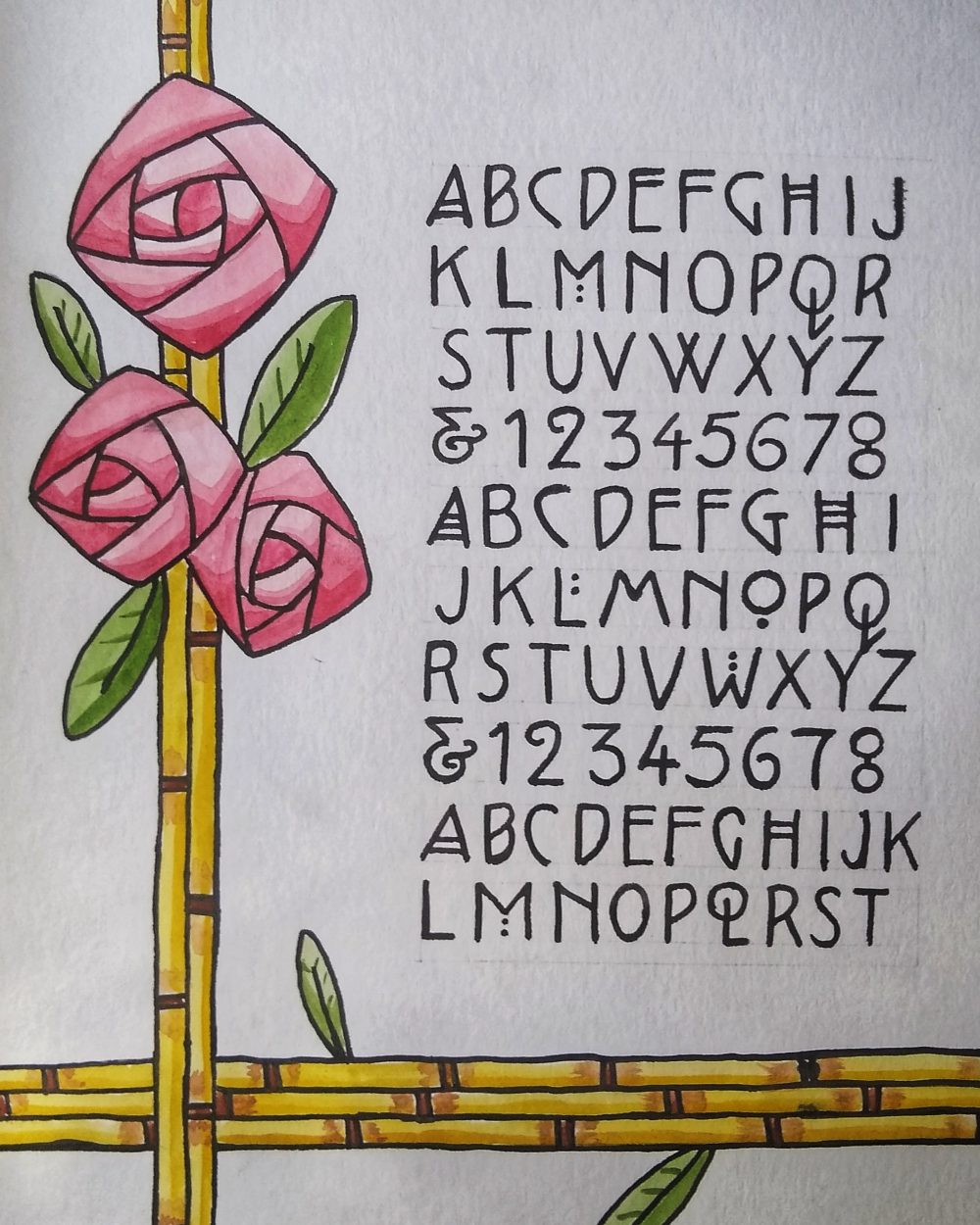 The piece is a full alphabet including numbers in an ornate block letter style, and framed on the left and bottom sides with some bamboo stalks and roses on the top left.