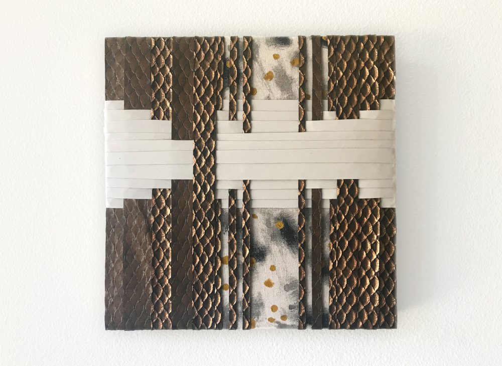 "A multi-colored and textural weaving of fabric and mixed medias on a wooden panel board with alternating strips of fabric layered on top of each other. "