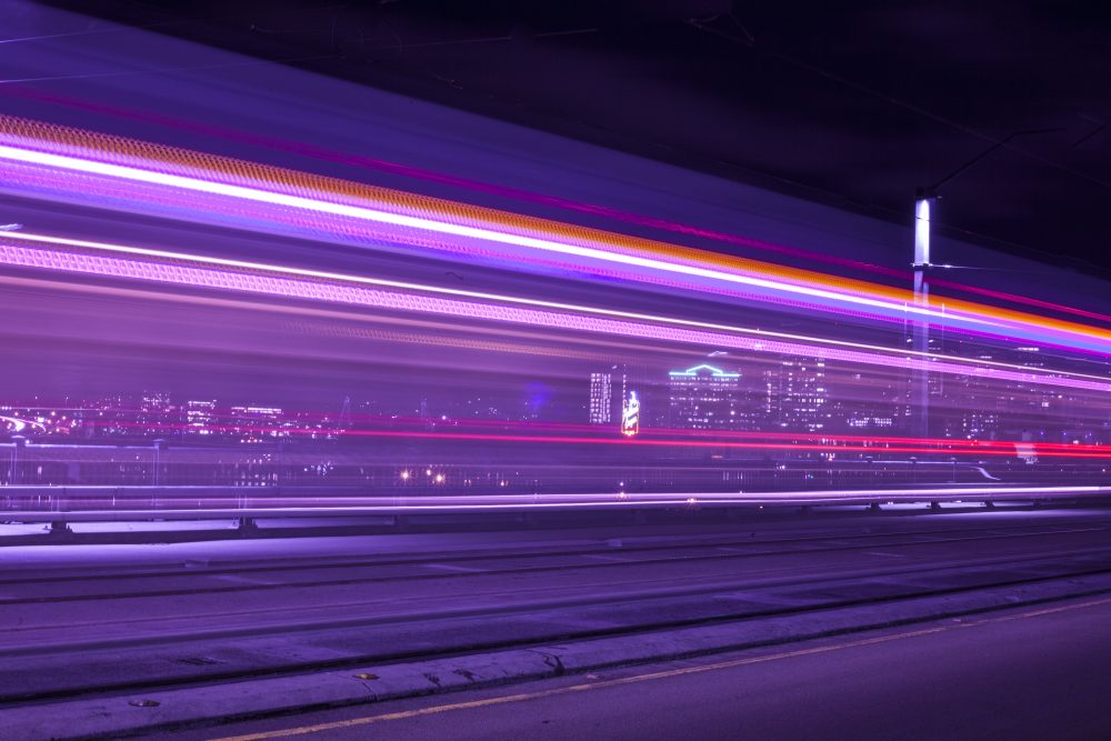 A stream of lights on a bridge with downtown Portland behind it.