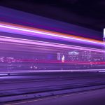 A stream of lights on a bridge with downtown Portland behind it.