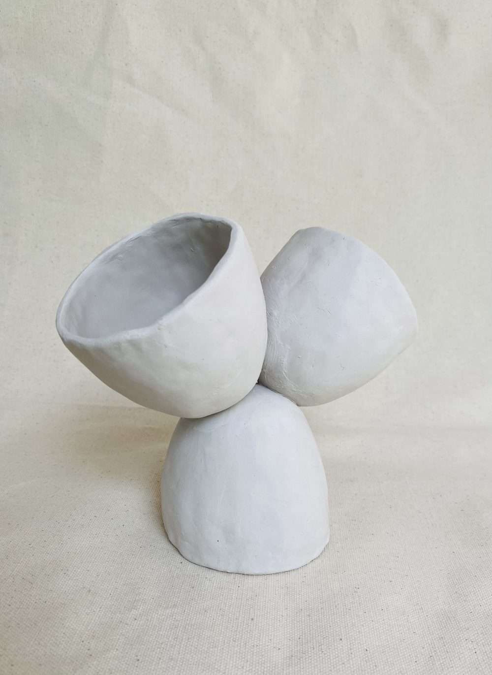 Three cups stacked: one at the base is upside down, while two are balanced atop it face-up