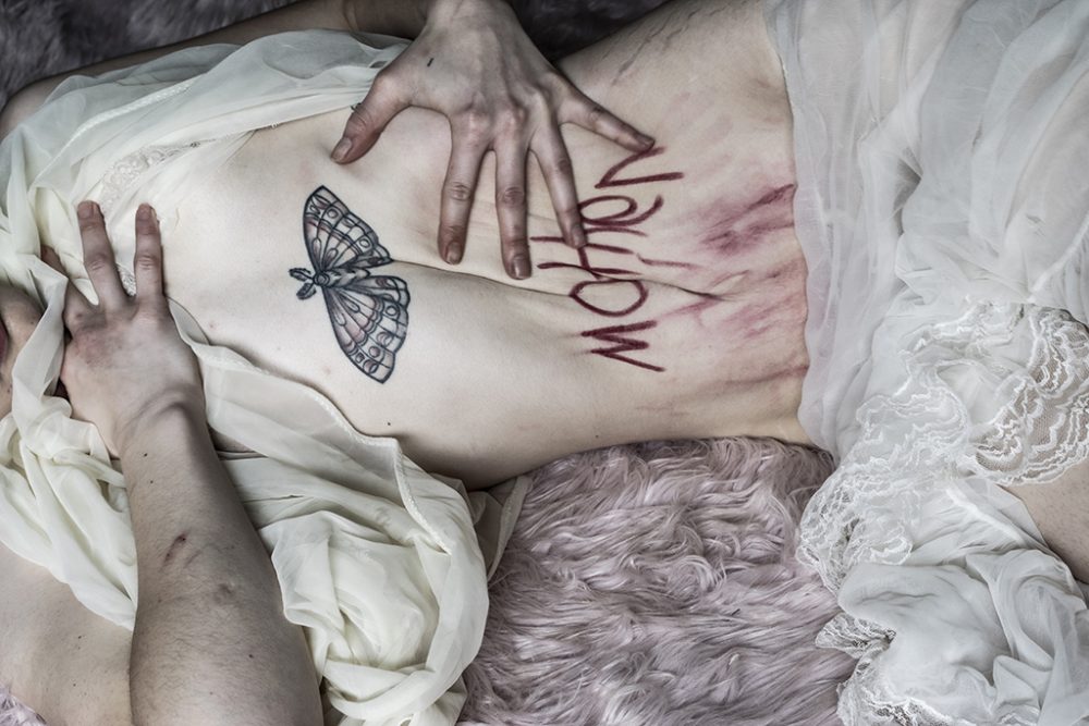 Bare stomach with the word Mother written in red on it.