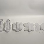 A polymer clay project in white of a shoe pair transforms to a butterfly.
