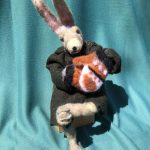This is a bunny figure made of wool felt sitting down with mittens and a jacket.