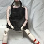 This is a 10 " tall figure made of ceramic body parts. The pieces are attached loosely with copper wire with a leather shop apron and painted features.