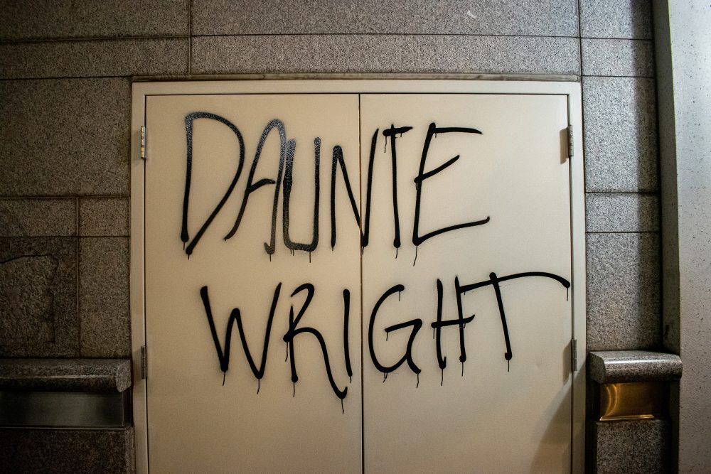 Photograph of the name "Daunte Wright" written all-caps in black spray paint over the exit doors of a building in downtown Portland.