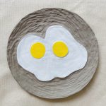 A plate, carved to reveal two free-form fried eggs in the center.