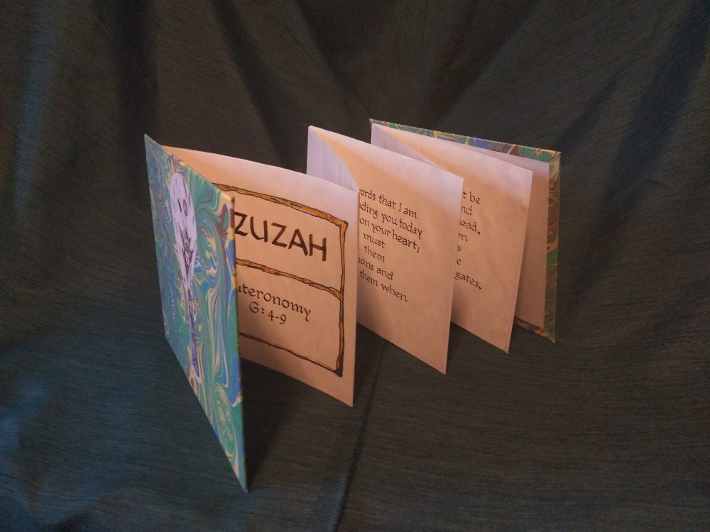 An accordion folded book with words from the Bible.