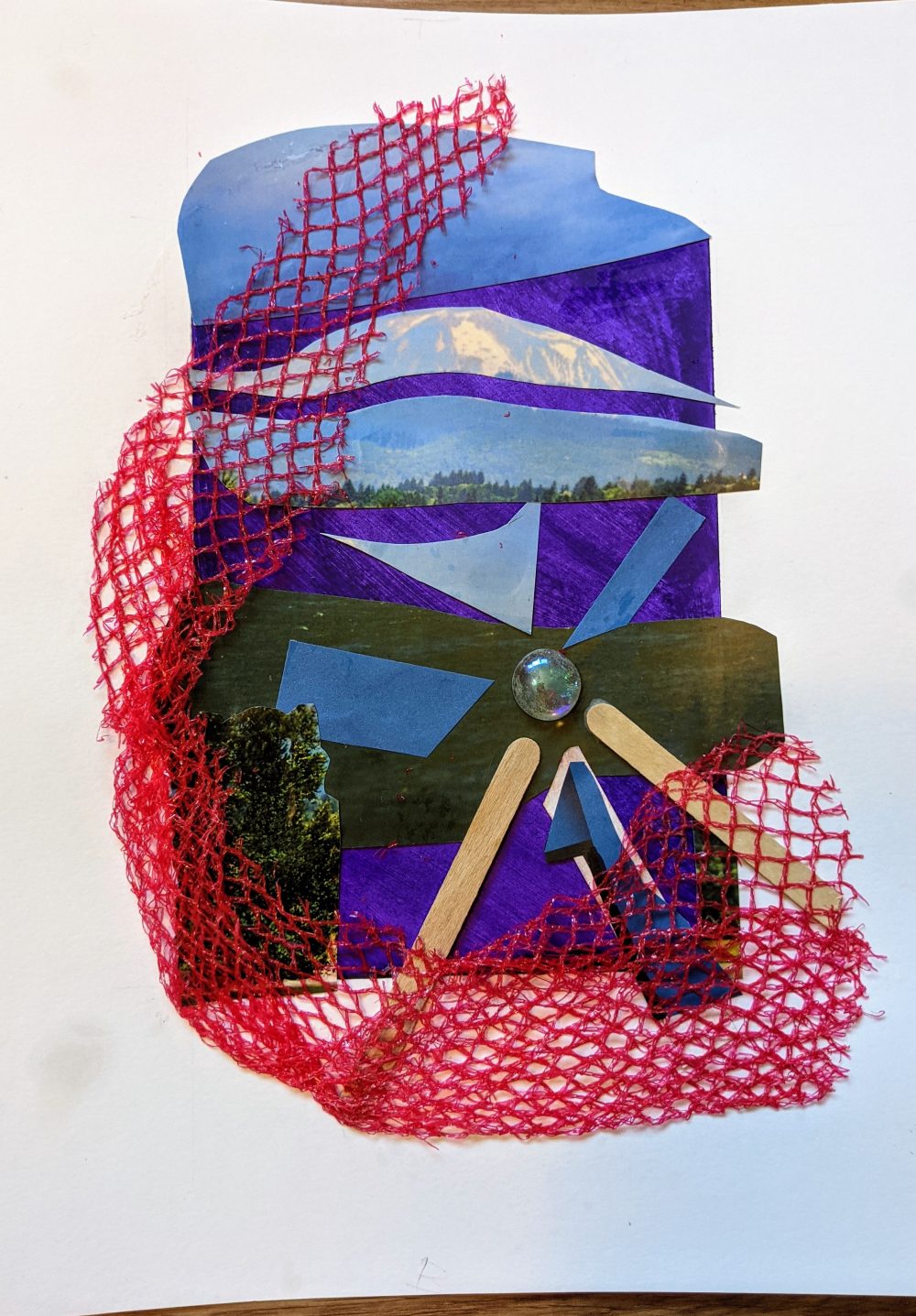A collage with paper, netting, stone, and sticks.