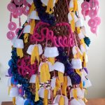 Hazel is made in a diamond shape from the front view with pink hair, small yogurt cups hanging all over the body, and many bright colors of material throughout.