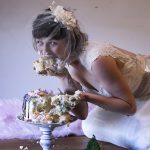 Person in a wedding dress eating cake with their hands.
