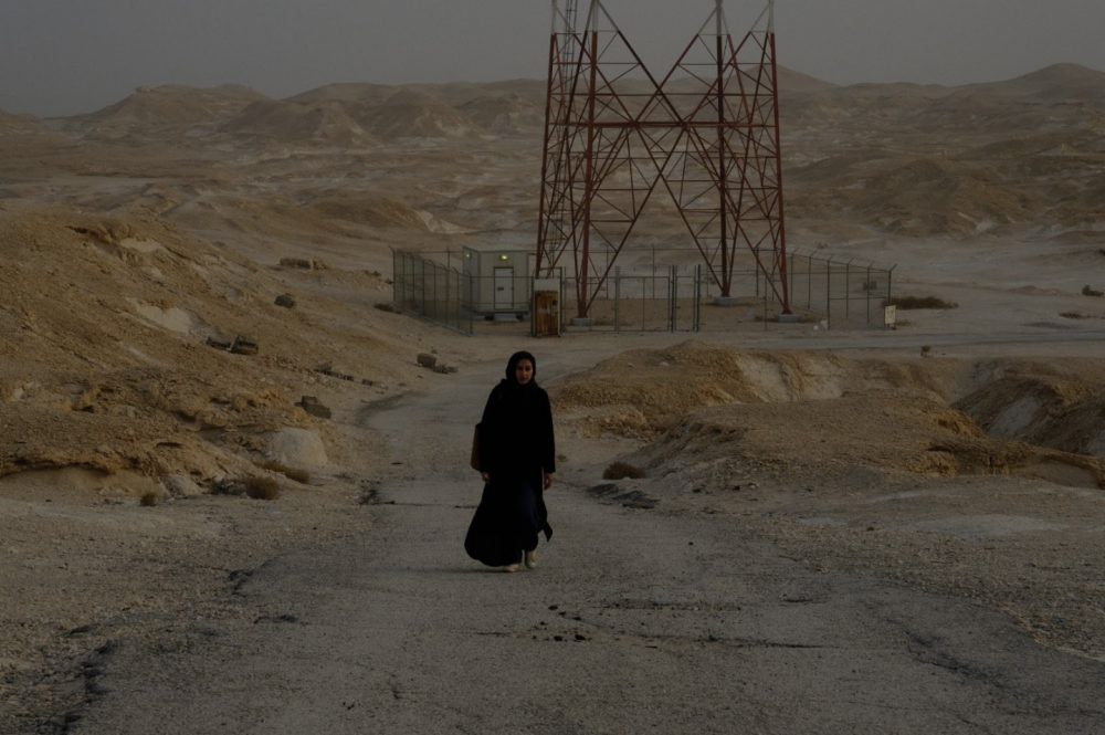 photograph of a figure walking in a desert-like landscape