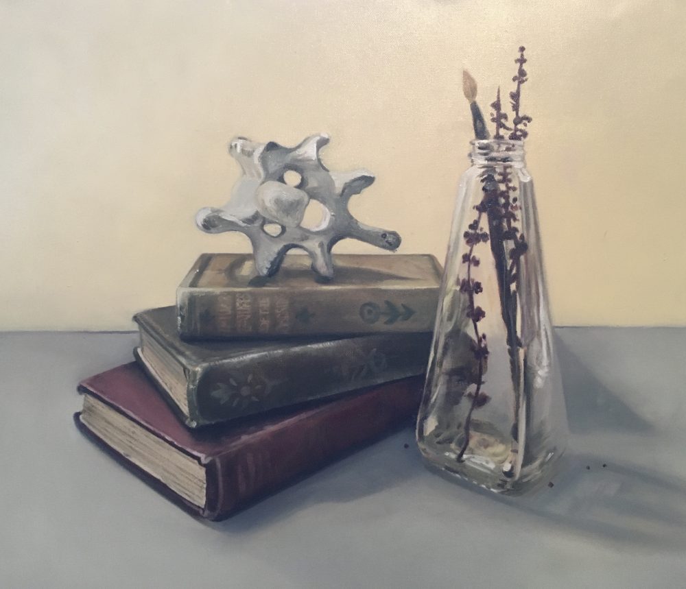 A still life oil painting of three antique books, a vertebra and a tall jar filled with some dried plants and a child's paintbrush.