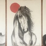 There are three black and white charcoal images of animals, a salmon on the left, a horse in the middle, and a raven on the right. Each are punctuated by a red-orange orb.