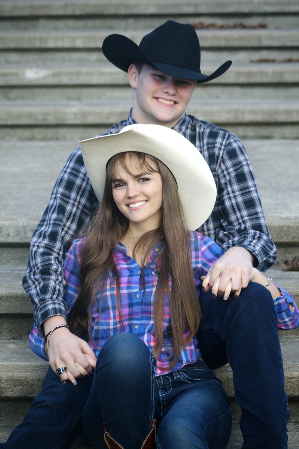 A photograph of a cowboy and cowgirl couple posing with vibrant colors and grey steps in the background.