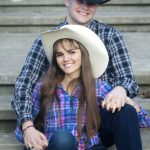 A photograph of a cowboy and cowgirl couple posing with vibrant colors and grey steps in the background.