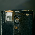 Color photo looking through the viewfinder of a Kodak Brownie at an old black and white photograph of a man standing behind a horse.