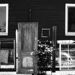 Black and white photo of a fence made with windows and a door.