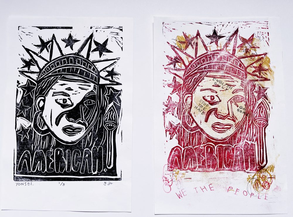 Two linocut prints with an Asian woman's face with the Statue of Liberty crown on her head and a torch nearby on the right side. The bottom of the print says "American" -- there are also stars around the crown area. The print on the left is in black. The print on the right is in red.