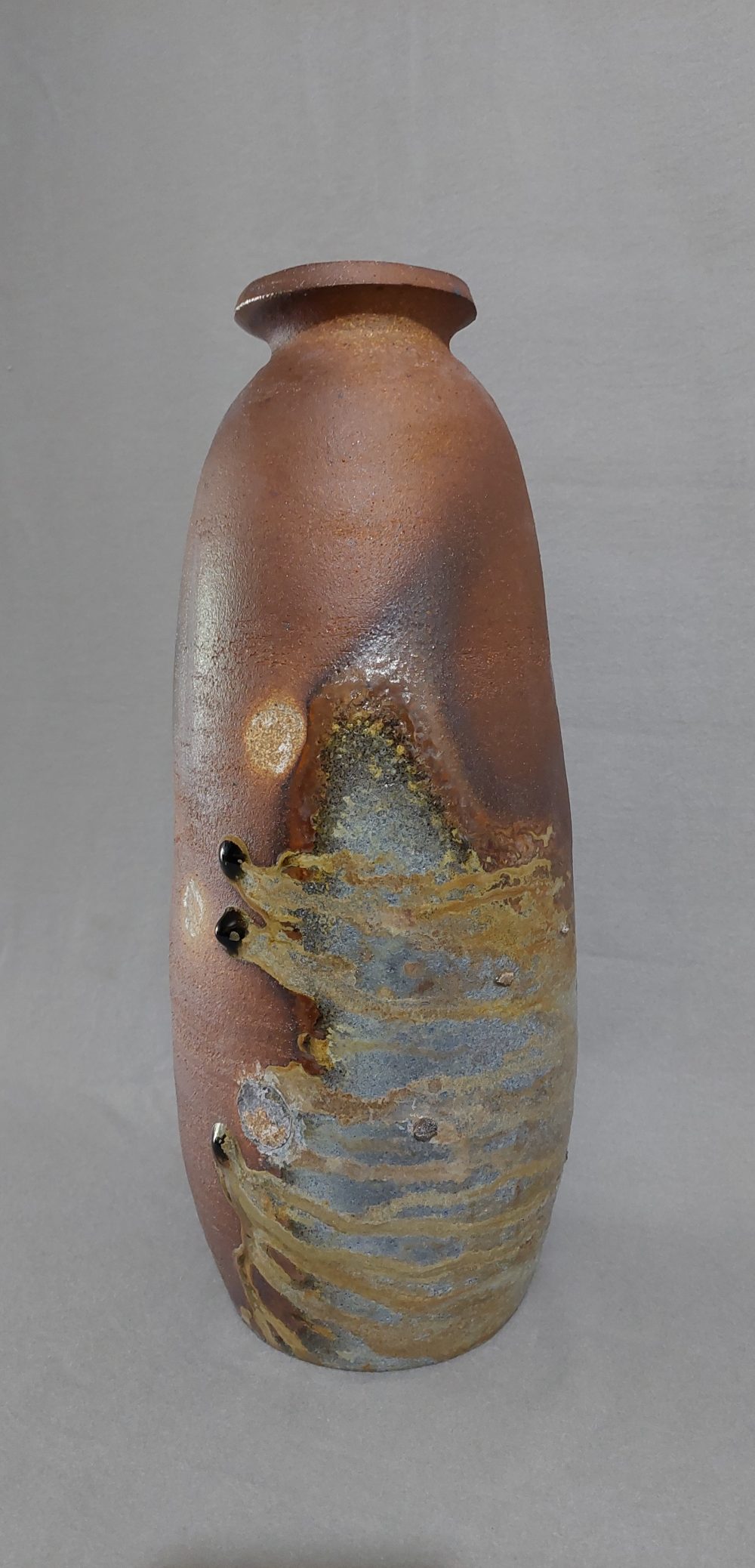 A tall vase with wood fire ash deposits for a surface finish.