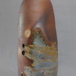 A tall vase with wood fire ash deposits for a surface finish.