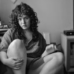 The photograph features myself sitting on a couch, with my livingroom being seen slightly in the background. The photo is in black and white.