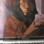 Painting is of a non binary individual using their computer screen as a mirror. They have long black hair and are wearing a red beret and a multicolored (red, green, yellow) sweater. In their hand is the phone they used to take a photo of themself in the reflection of the computer screen. Their eyes are not on their face, but one is subtly positioned on the lens of the phone camera. The photo includes the screen and part of the keyboard of their computer.