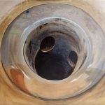 A painting of a close-up view of a drain and the pipe.
