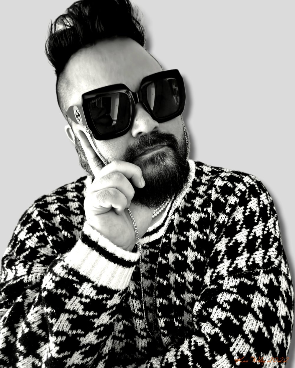 A black and white photo of a man in fashionable attire in a thinking pose.