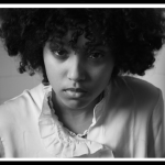 A black and white photo of a young person staring into the camera.