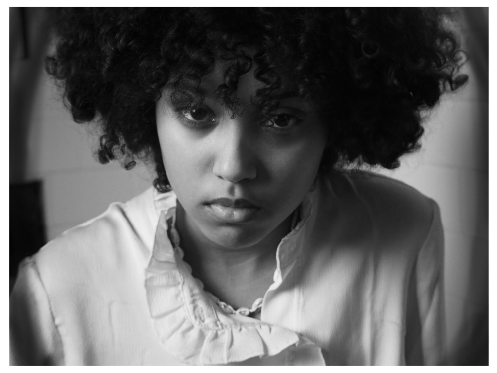 A black and white photo of a young person staring into the camera.