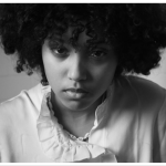 A black and white photo of a young person staring into the camera.