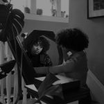 A black and white photo of a person staring into their reflection.