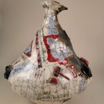 A large, off-centered and wonky pot, decorated with 2D slip and glaze designs in light blue, red, and black, and 3D medallions sculpted into various shapes, glazed, and attached to the surface of the pot.