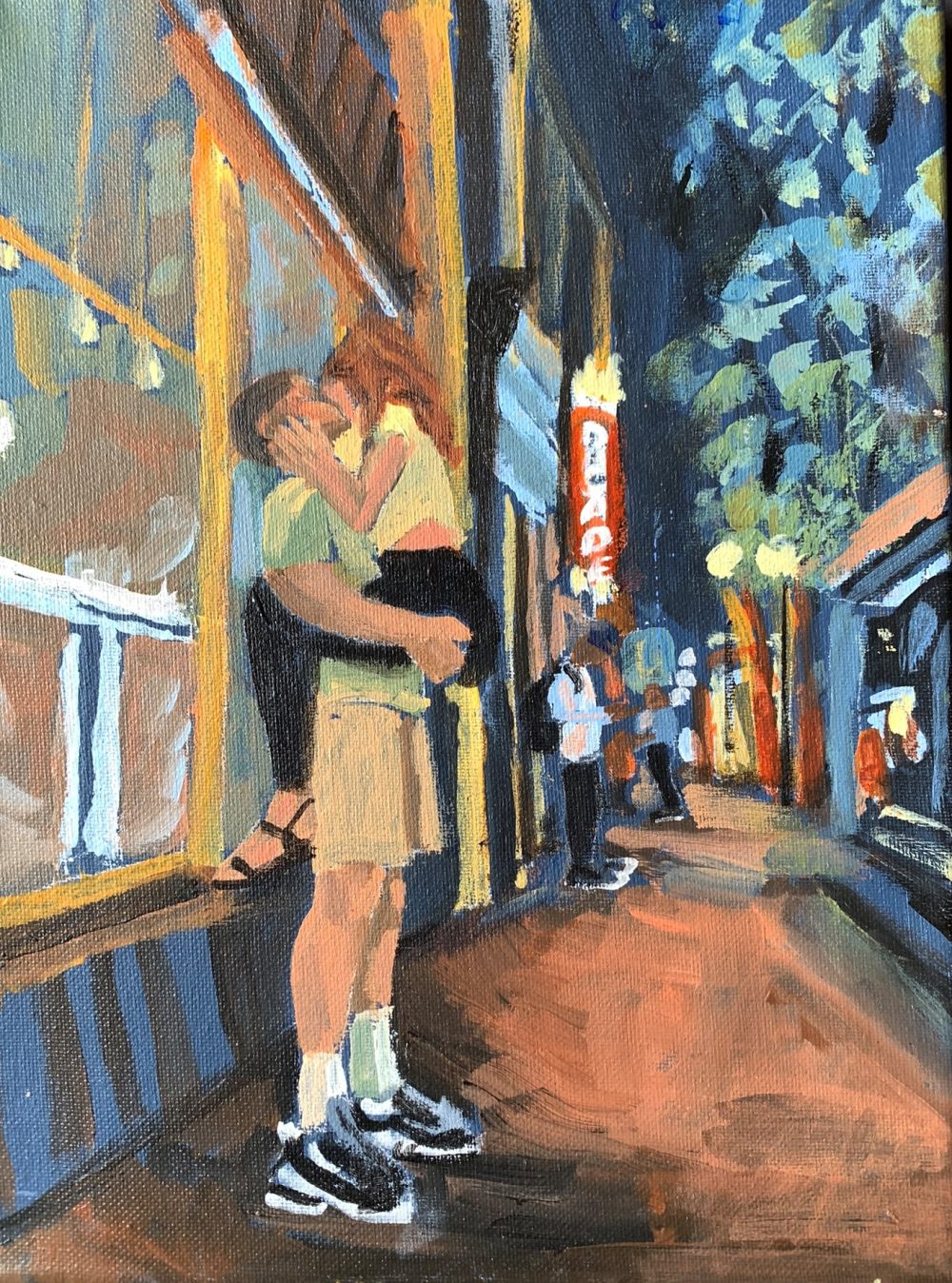 A young man holds and kisses a young woman in downtown Portland at night.