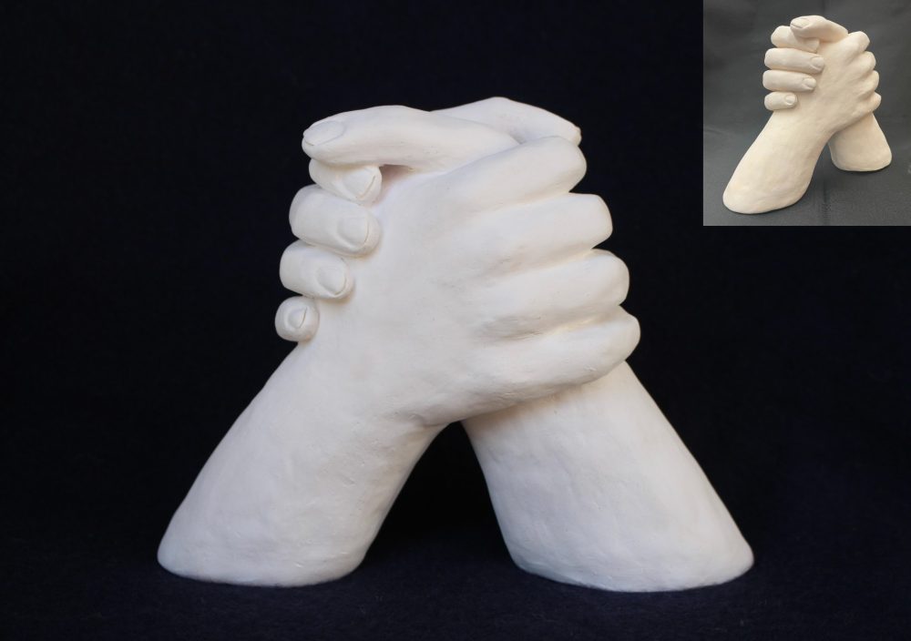 A 3D sculpture of 2 hands clasped together.