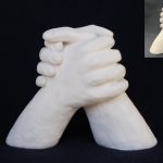 A 3D sculpture of 2 hands clasped together.