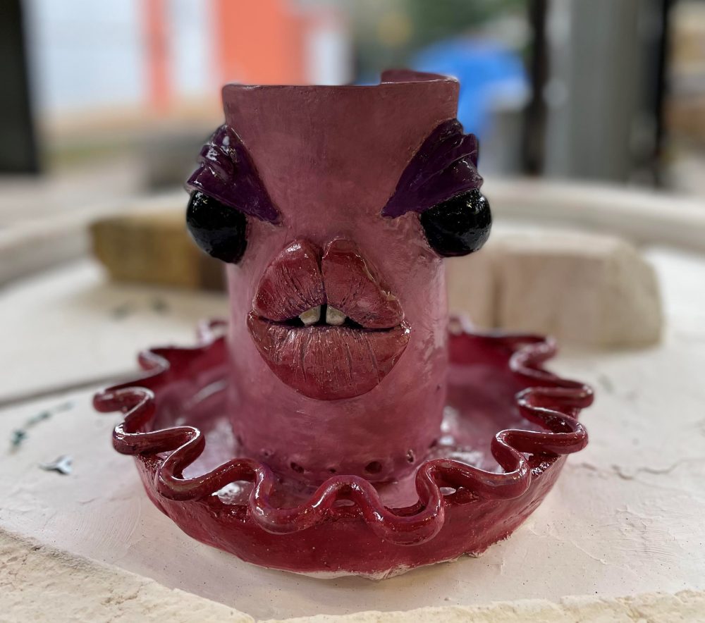 A pink ceramic planter with exaggerated, alien-like facial features.