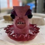 A pink ceramic planter with exaggerated, alien-like facial features.