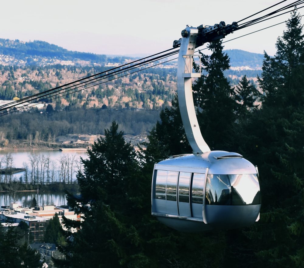 OHSU tram going up with view of Portland in the background.