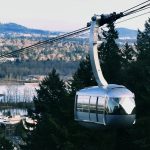 OHSU tram going up with view of Portland in the background.