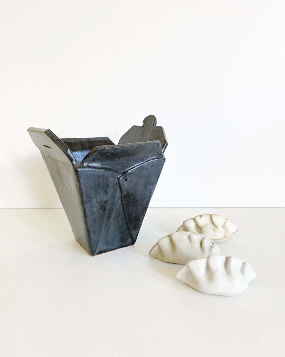 A black takeout-style box, with three glazed dumplings.