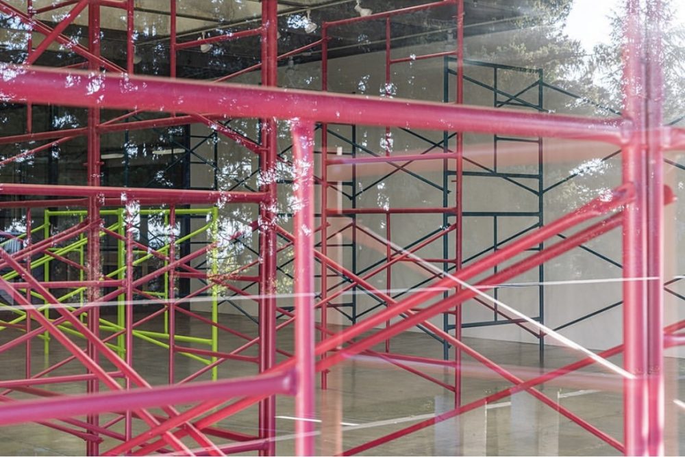 Photograph of pink and green scaffolding in a gallery.