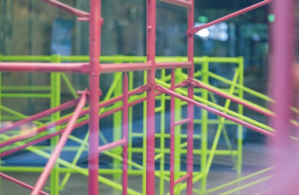 Green and pink scaffolding in a gallery.