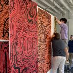 Students hang drawings on the gallery walls.